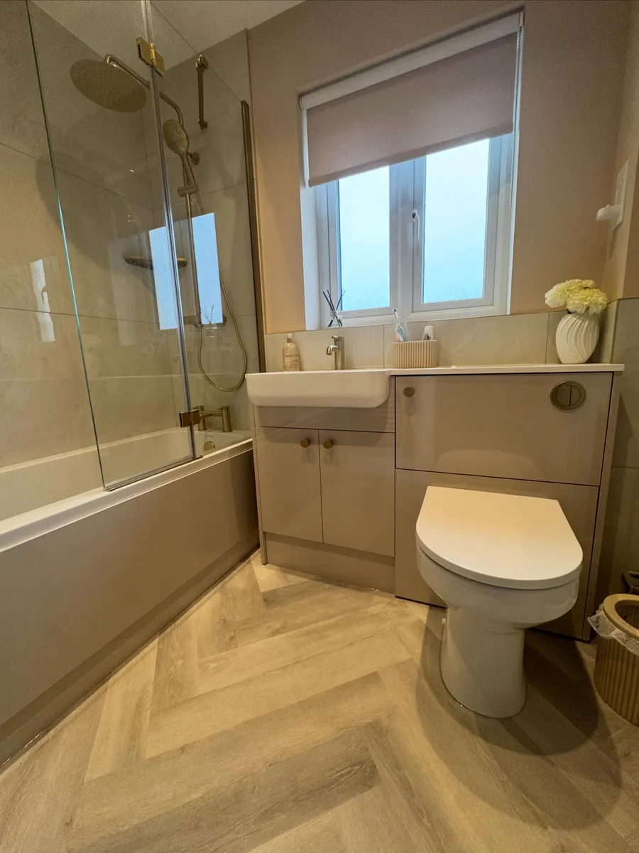 After: bath with glass shower screen, grey vanity unit and herringbone floor