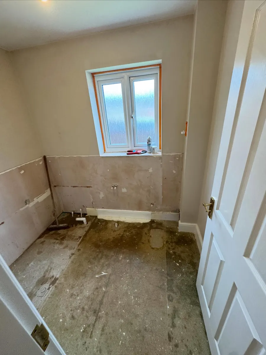 Before: the same room stripped out, bare floor and capped pipework under the window