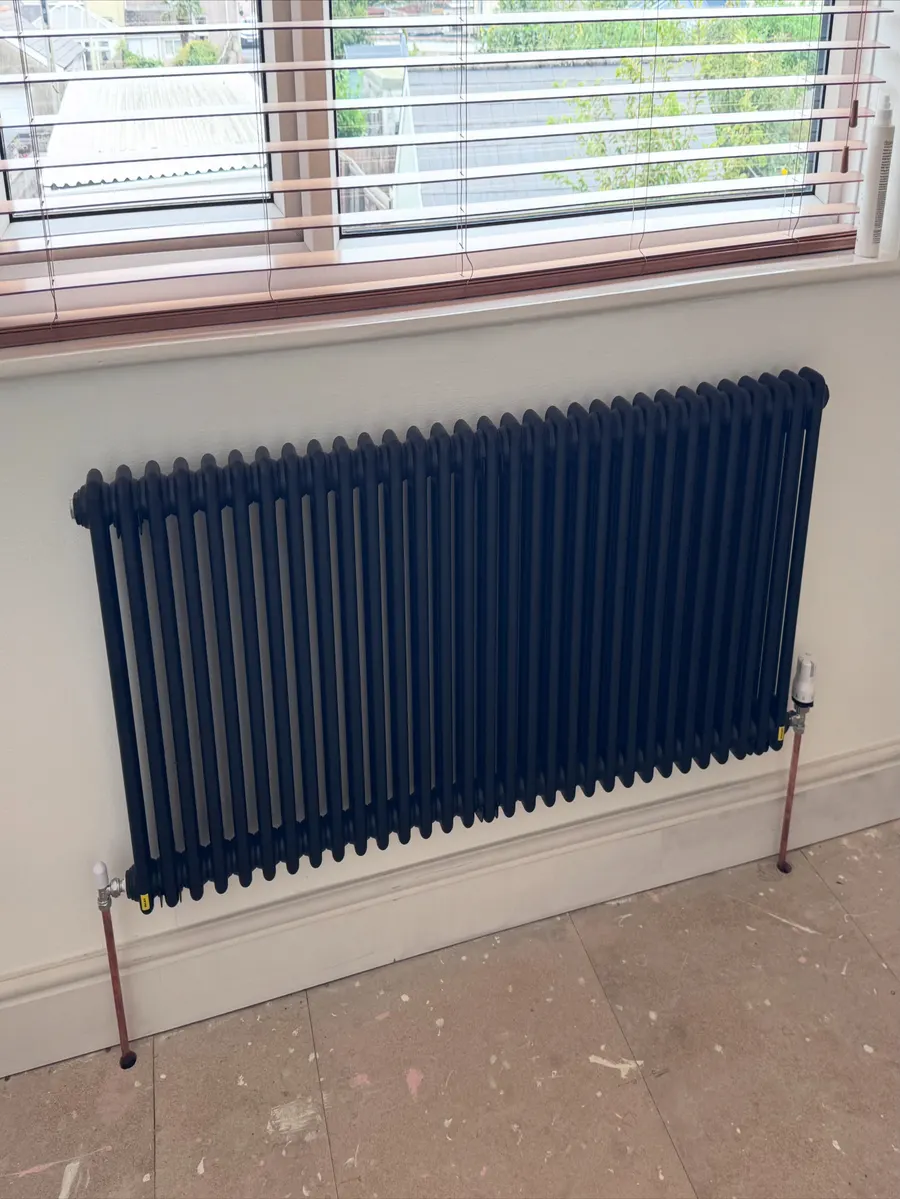 Anthracite column radiator fitted under a living room window