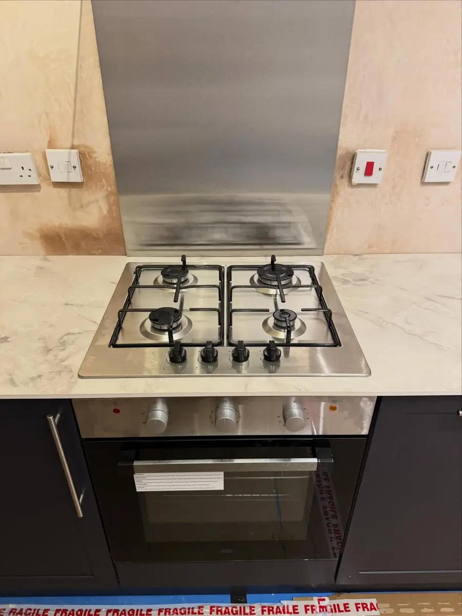 Stainless gas hob above a built-in oven in a new kitchen