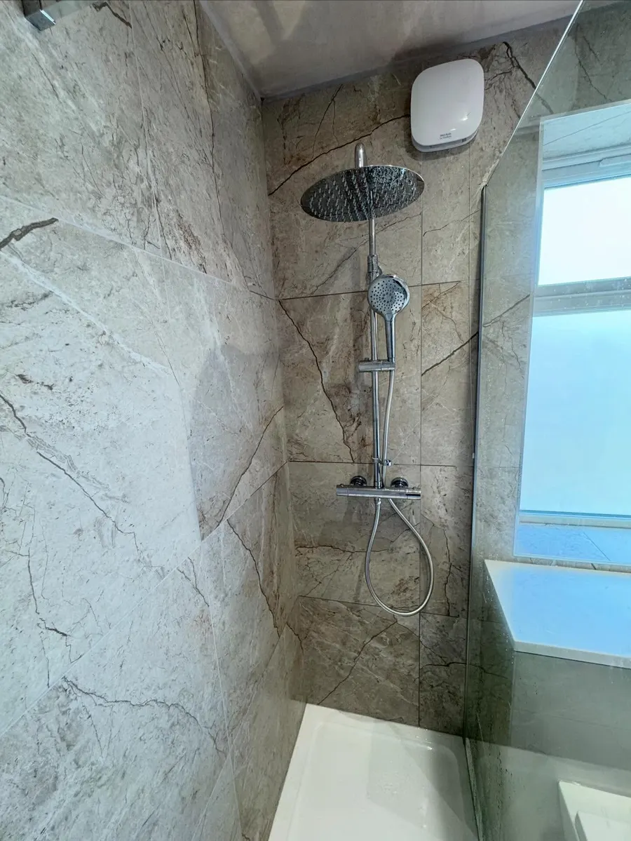 Walk-in shower with a rainfall head and grey marble-effect wall panels