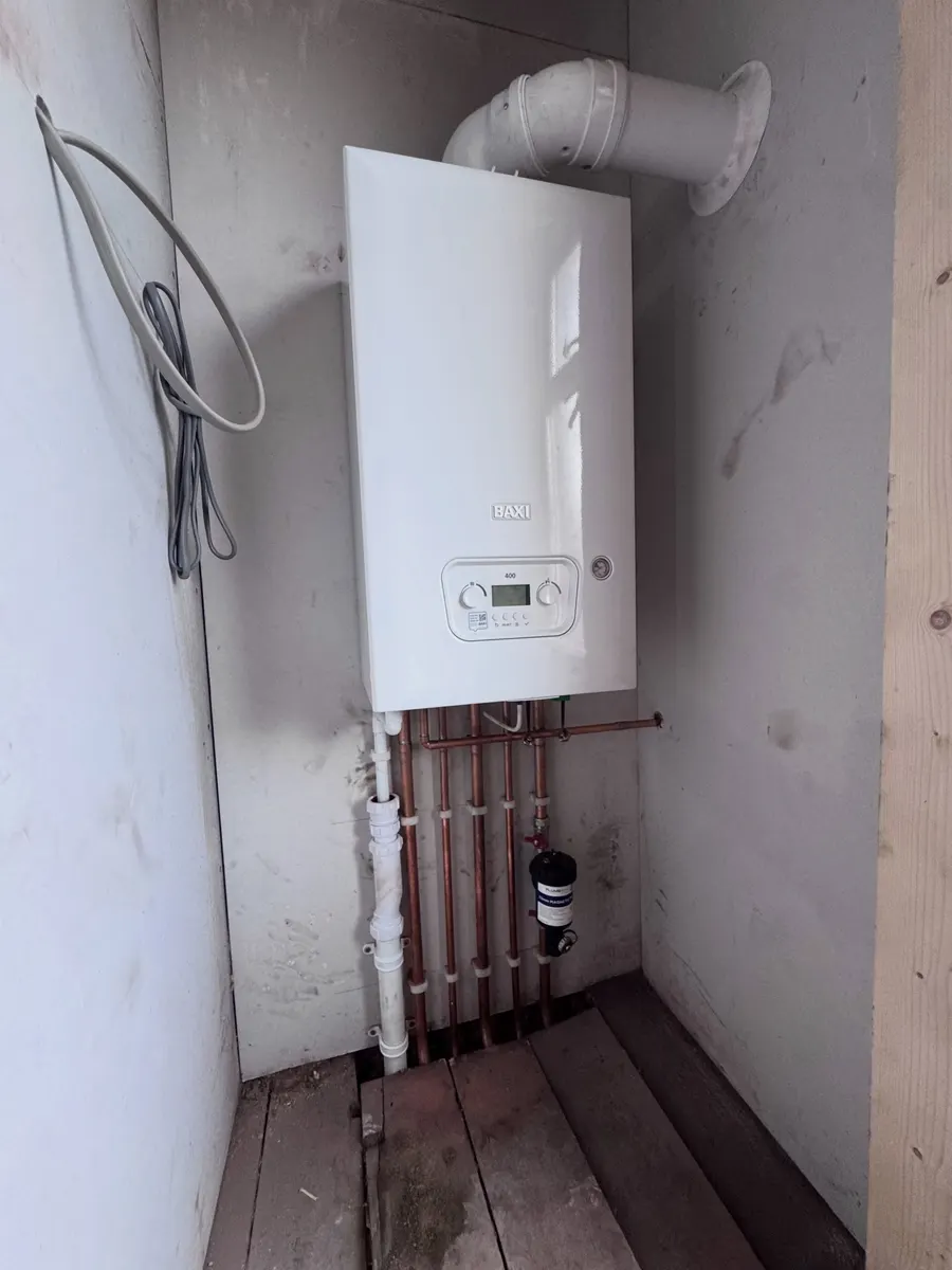 New white combi boiler fitted on a wall with copper pipework below