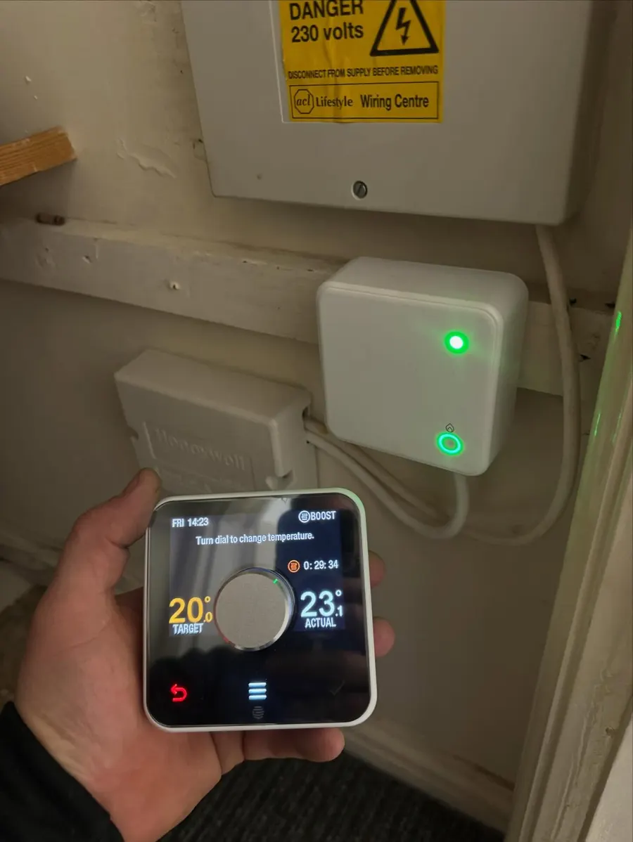 Smart thermostat being set up in hand next to its wall receiver