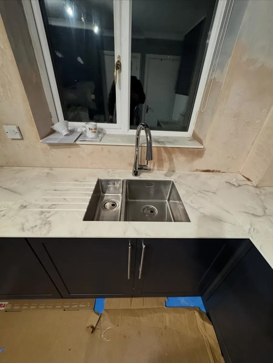 Stainless undermount kitchen sink with a black mixer tap on a marble-effect worktop