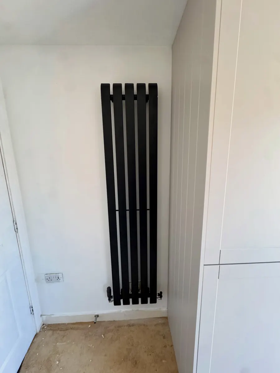 Slim black vertical radiator in a newly decorated hallway